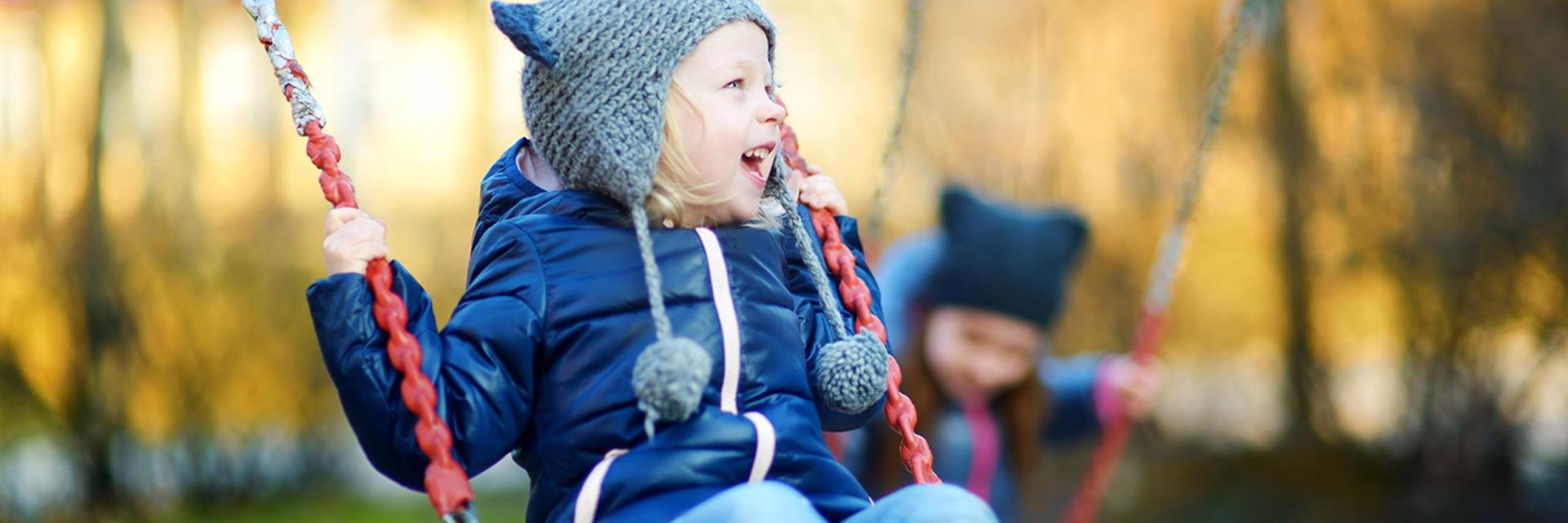 Bilde av et barn i utelek som ler hjertelig